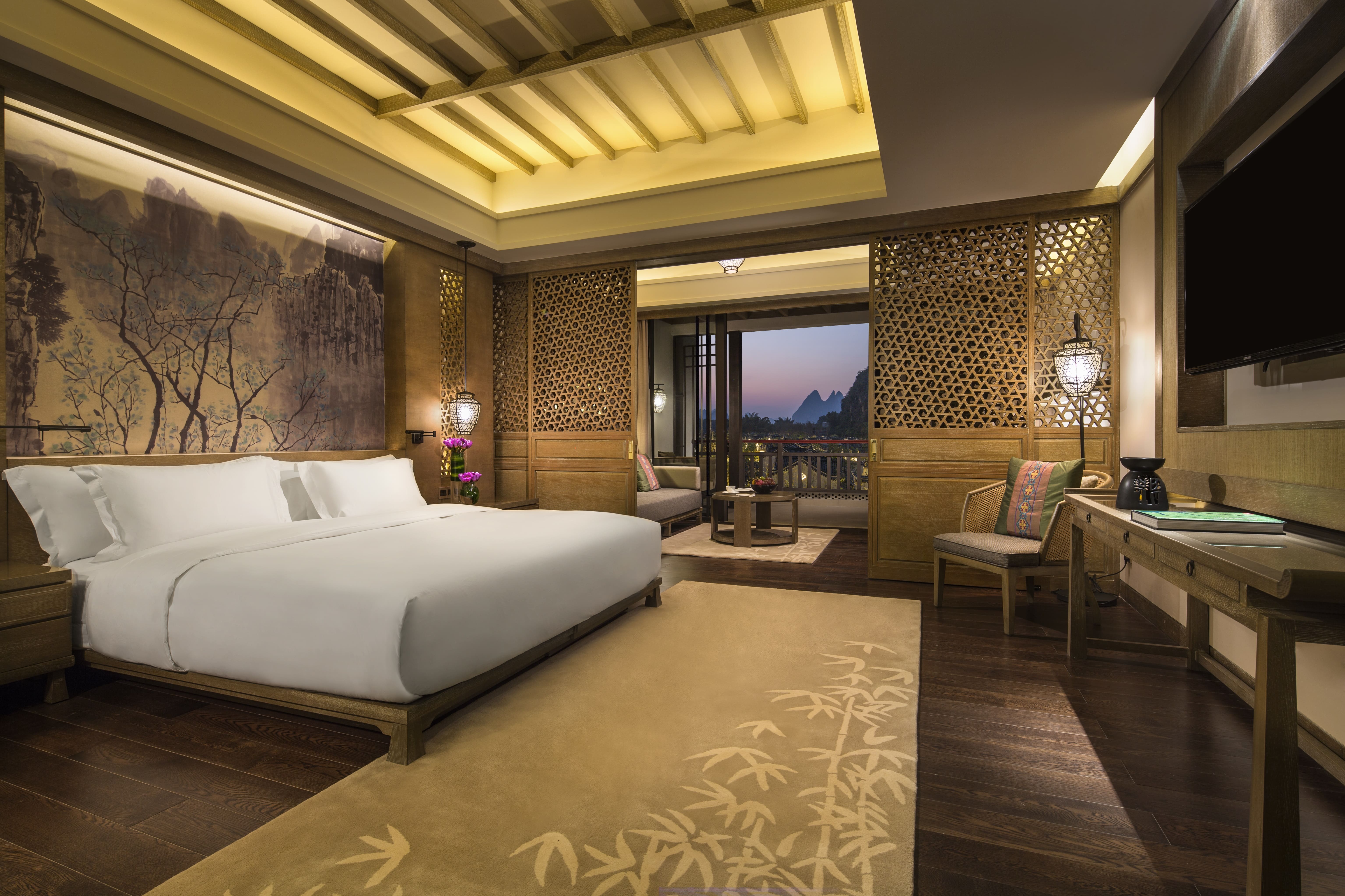 Luxurious Banyan Tree Yangshuo bedroom with elegant decor, overlooking a scenic balcony view.